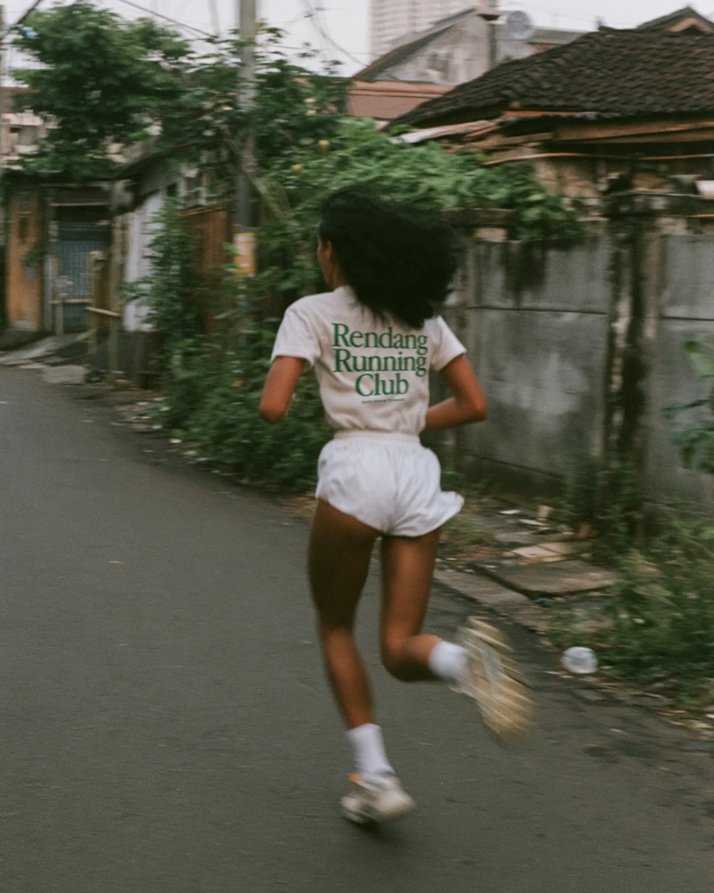 A runner in the Rendang Running Club tee on a neighborhood street